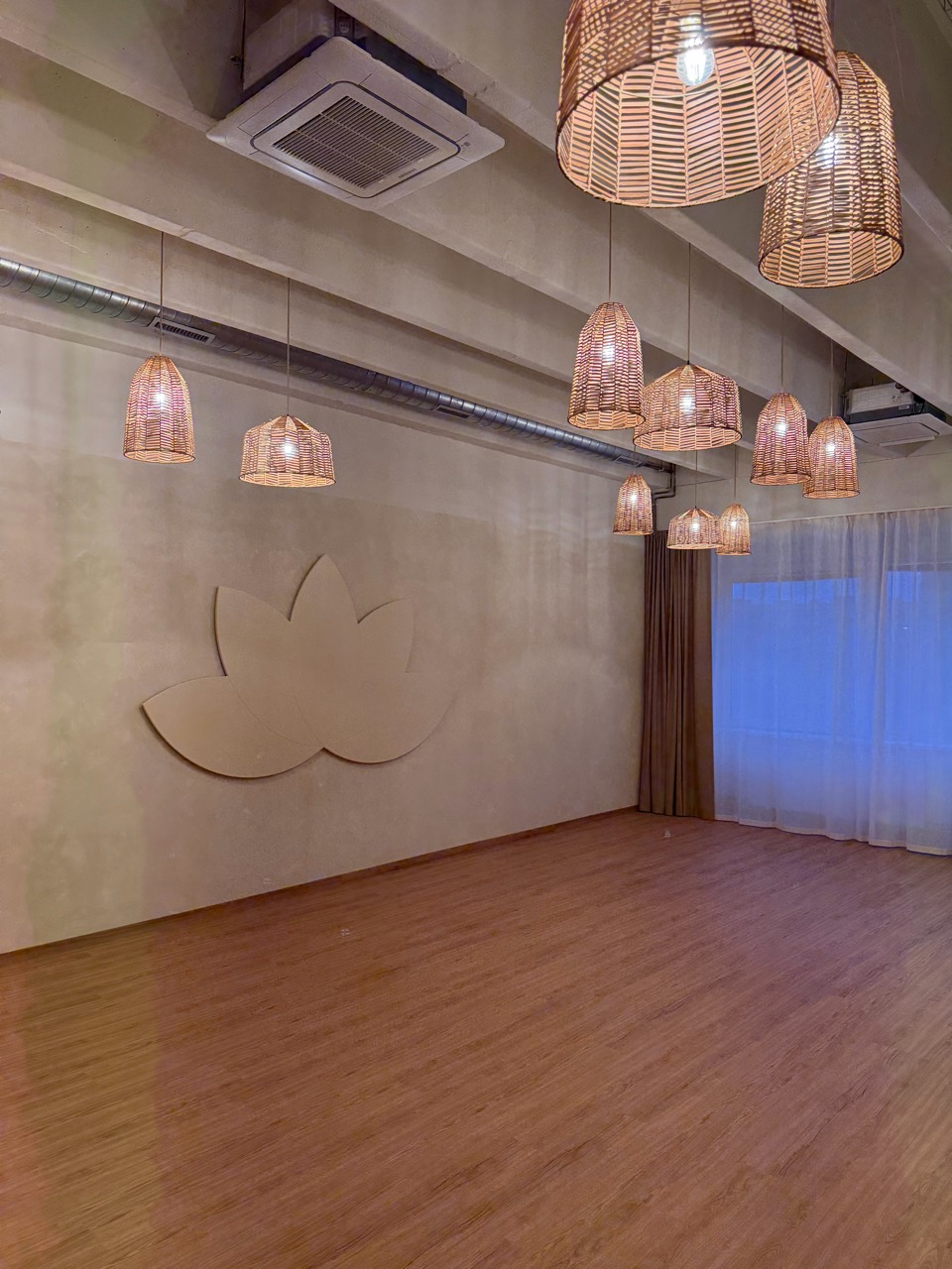 Jógové studio s lotosovým symbolem, proutěnými lampami a dřevěnou podlahou